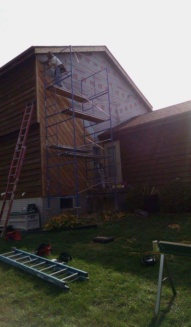 Skelley Construction, Inc. - unique wooden house siding installation with Construction Worker balancing on scaffolding - Decatur, IL